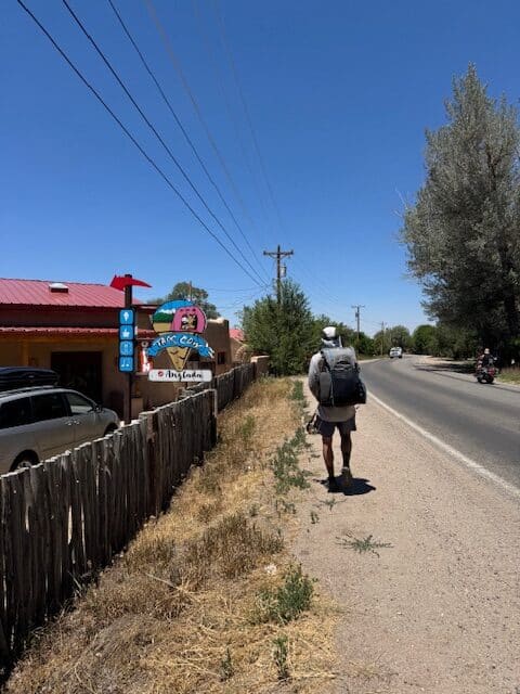 Hiker walking along a rural road near Santa Fe to Taos Thru-Hike route.