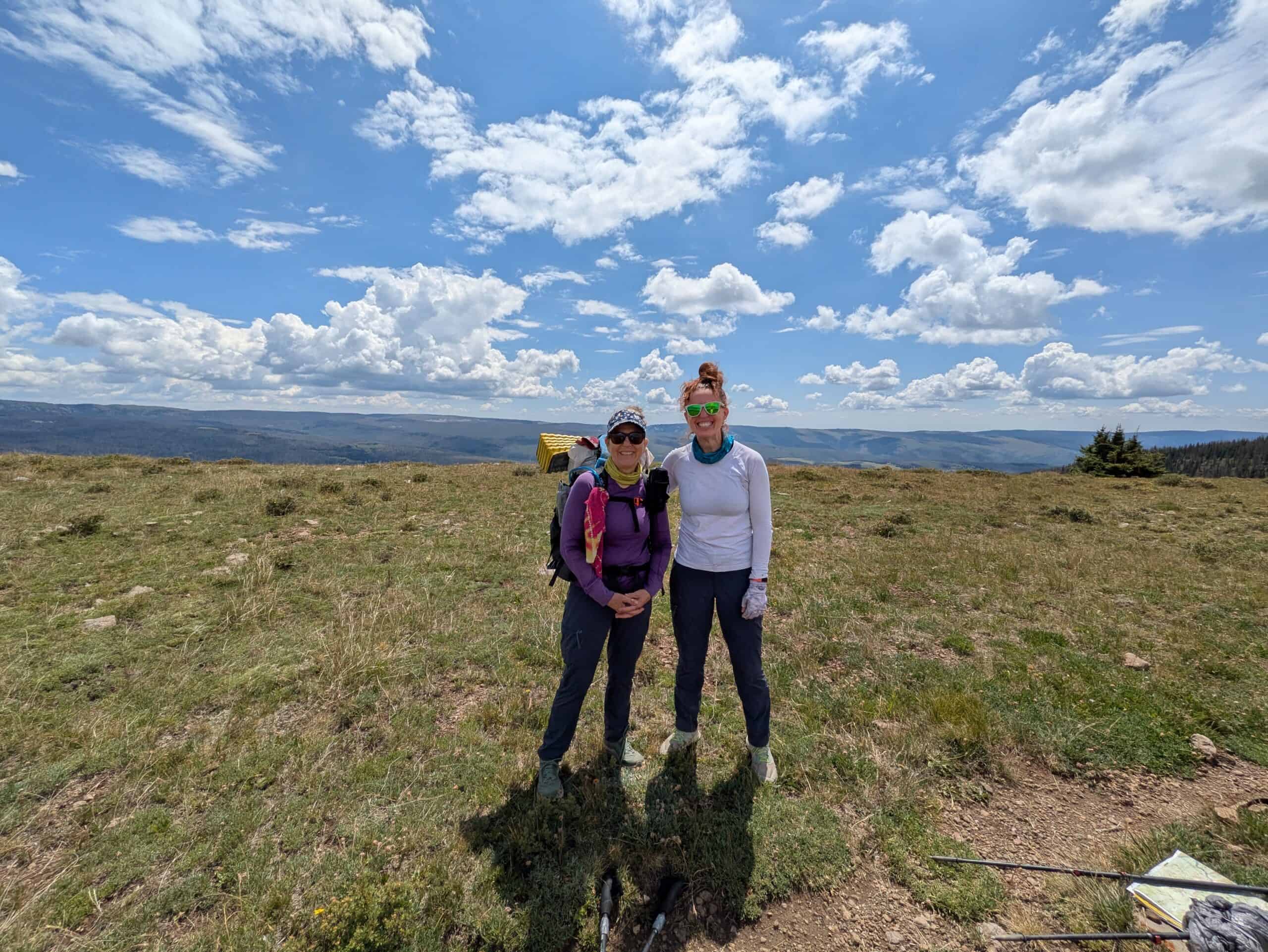 Hikers on the Santa Fe to Taos Thru-Hike trail with scenic mountain views.