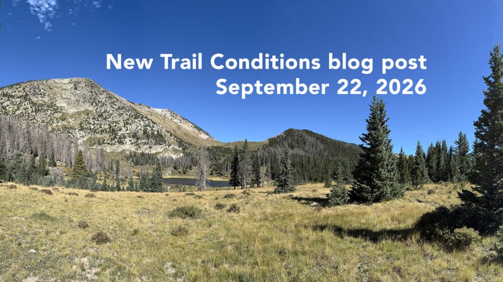 Scenic view of mountain trail with trees and blue sky, September 2026.