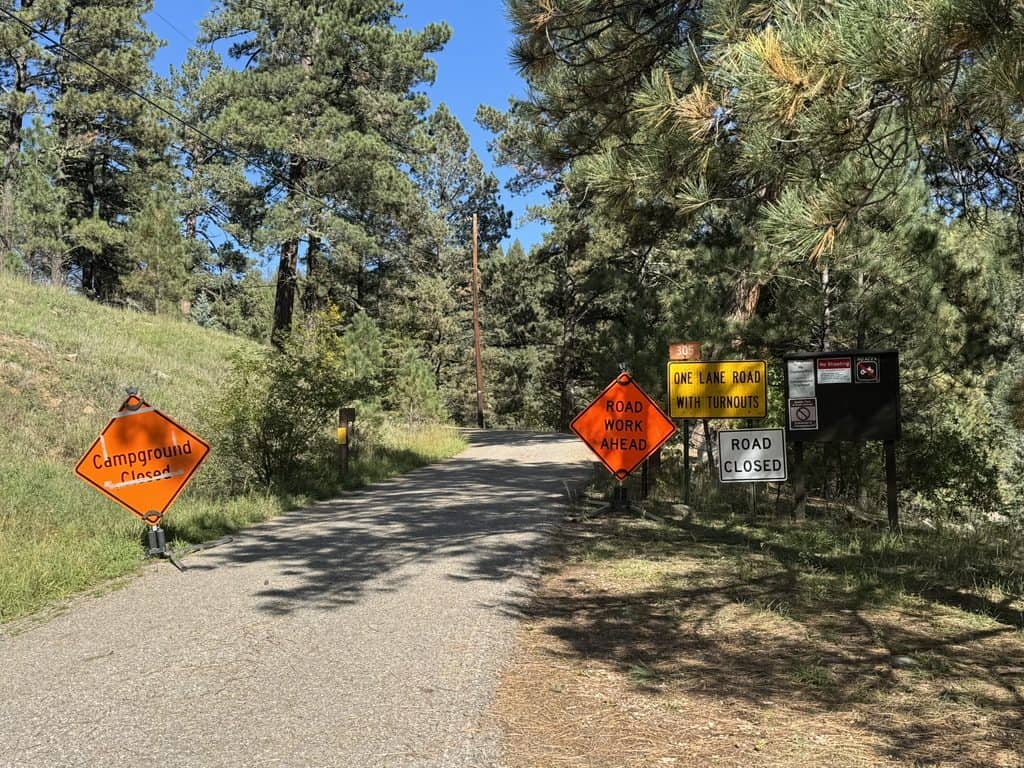 Closed campground road with warning signs and trees in Santa Fe to Taos hike area.